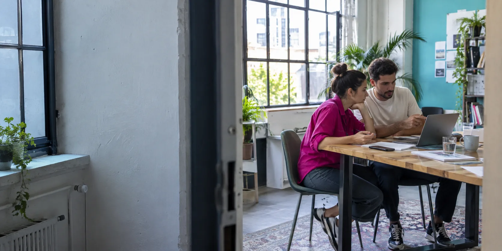 An agency reviews a client's work at a table beside a window.